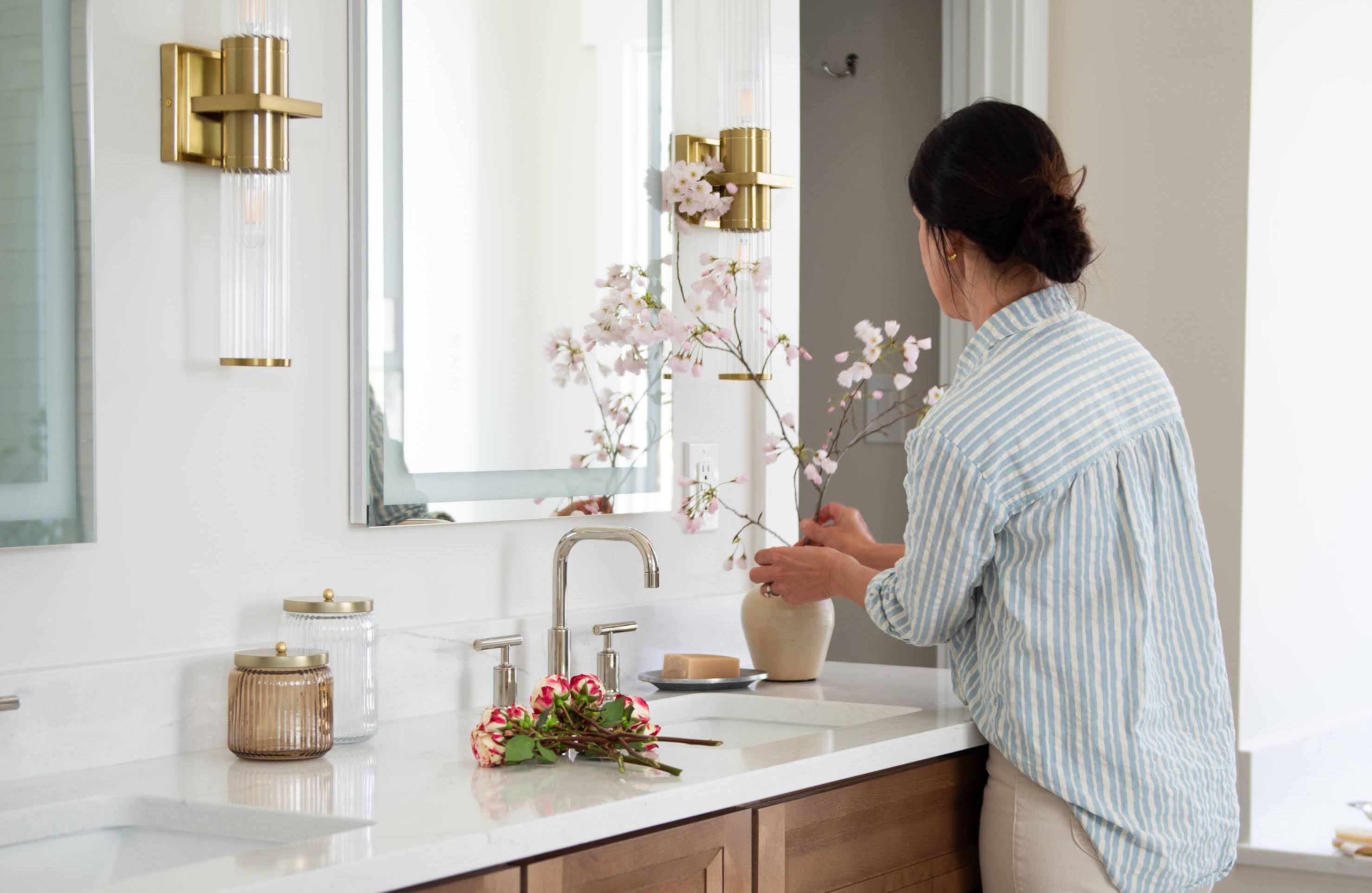 Woman arranging flowers in bathroom
