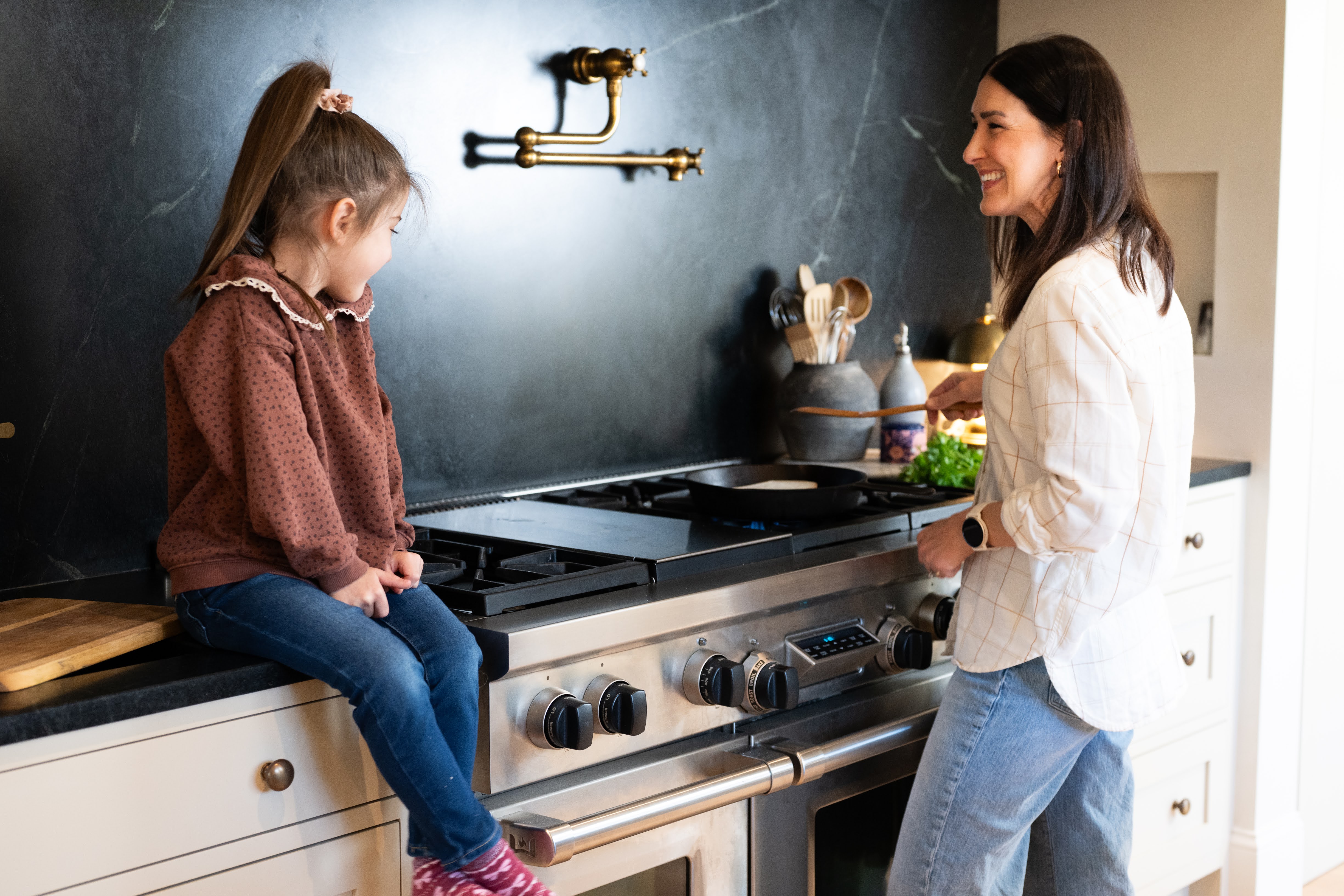 Woman cooking in kitchen with child on counter